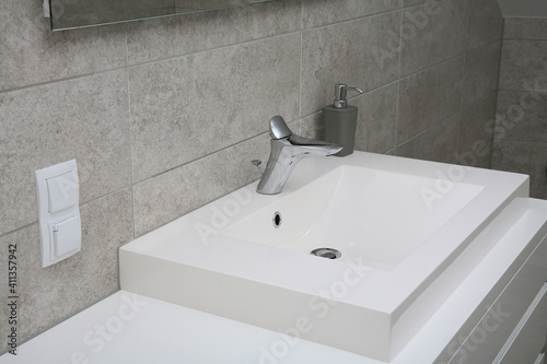 A white washbasin with a tap in a modern apartment 
