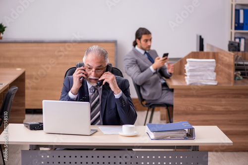 Old boss and young male assistant in the office