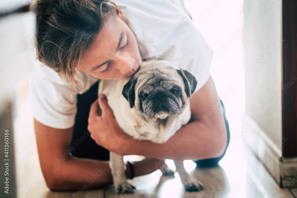 couple of teenager and cute white pug - love and affection of two best frieds at home - loving the animals couple of teenager and cute white pug - love and affection of two best frieds at home - loving the animals