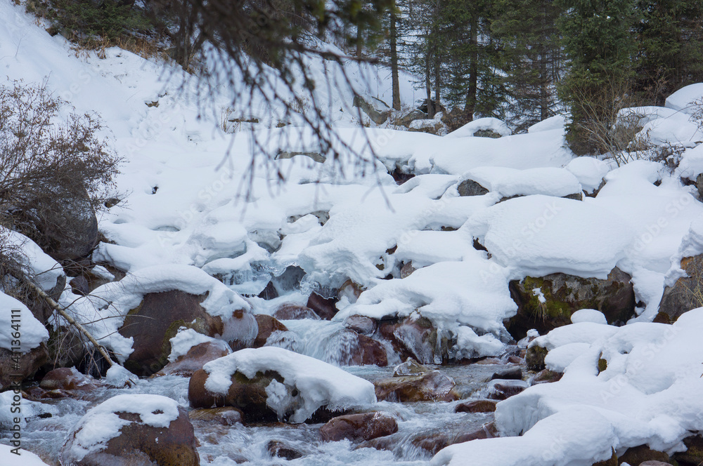 Mountain river among stones and snow.