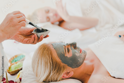 A young woman using a black mud mask in the spa. For facial treatment by spa staff