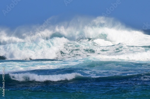 A tropical storm in the Pacific ocean, creating massive waves along the shoreline photo