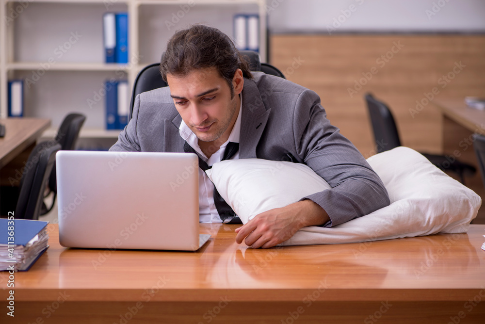Young male employee sleeping at workplace