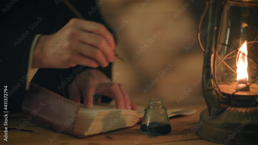 Nineteenth century scene lit by the warm glowing light from an oil lantern of a man writing in a journal using a dip pen.