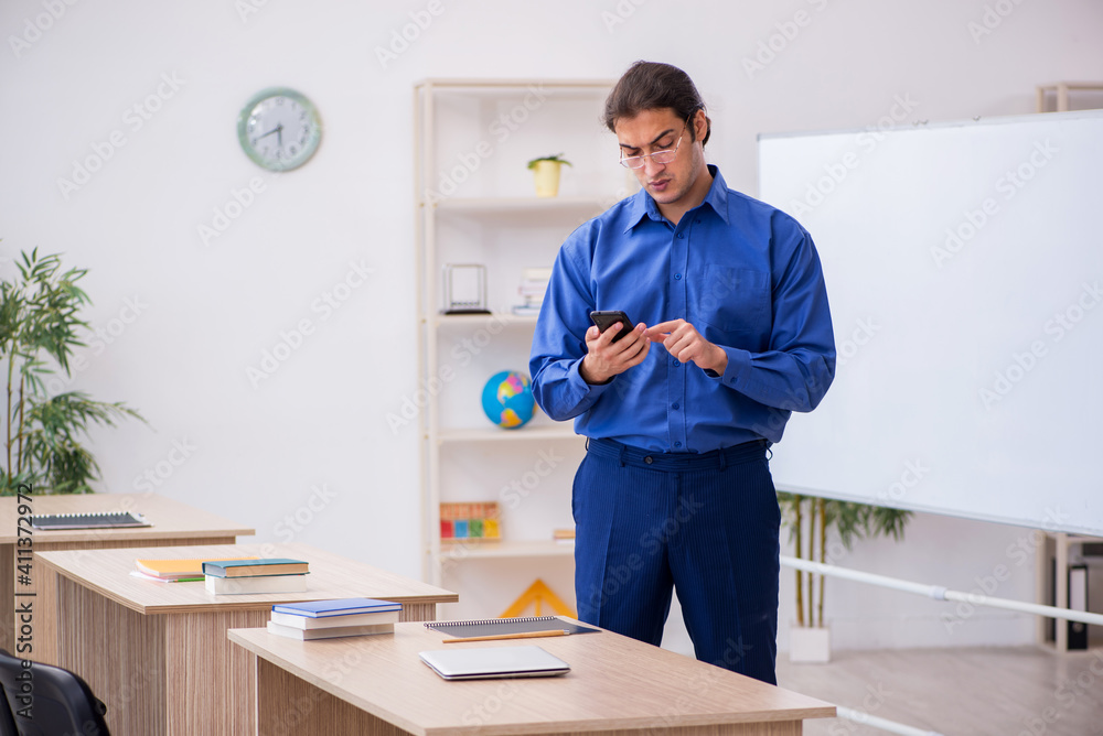 Young male teacher holding smartphone during lesson