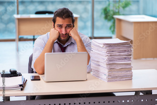 Young male employee unhappy with excessive work in the office