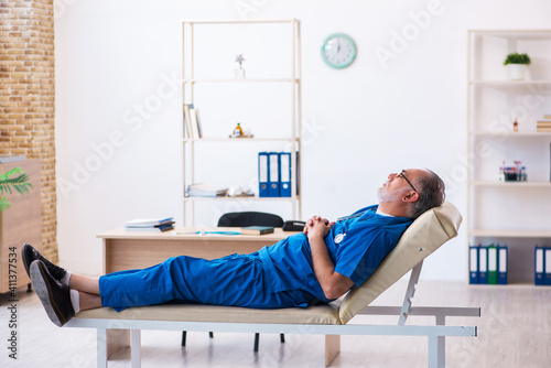 Old male doctor extremely tired after night shift