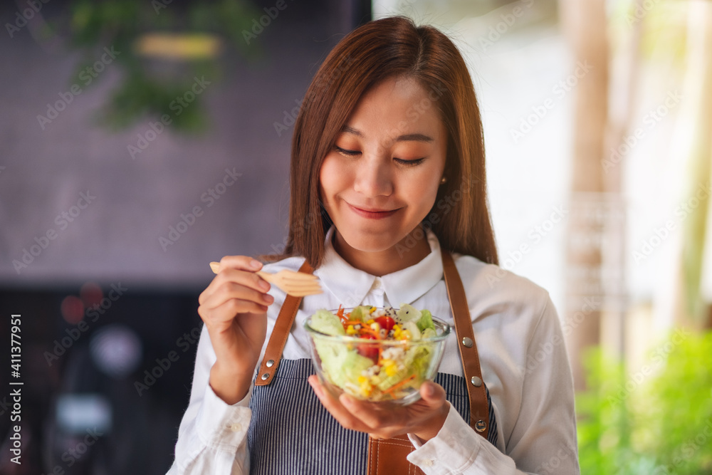Closeup image of a beautiful young female chef holding and eating fresh mixed vegetables salad Closeup image of a beautiful young female chef holding and eating fresh mixed vegetables salad