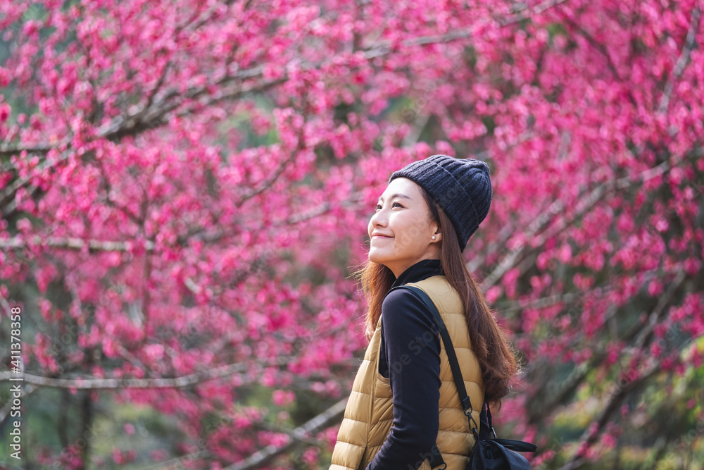 Portrait image of a beautiful young asian woman with pink cherry blossom flower in background Portrait image of a beautiful young asian woman with pink cherry blossom flower in background