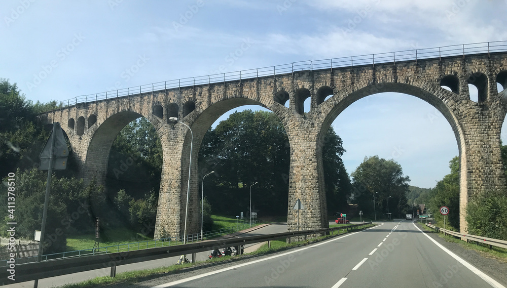 Fototapeta premium Old arched stone bridge over a road in Germany