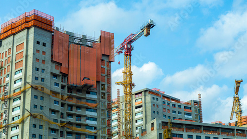 construction site with cranes and apartments on the background blue sky