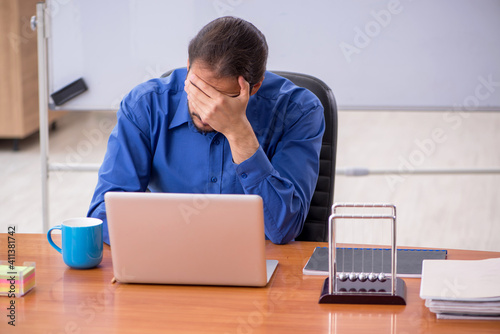 Young male teacher physicist sitting in the classroom photo