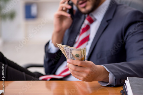 Young male employee holding banknotes in the office