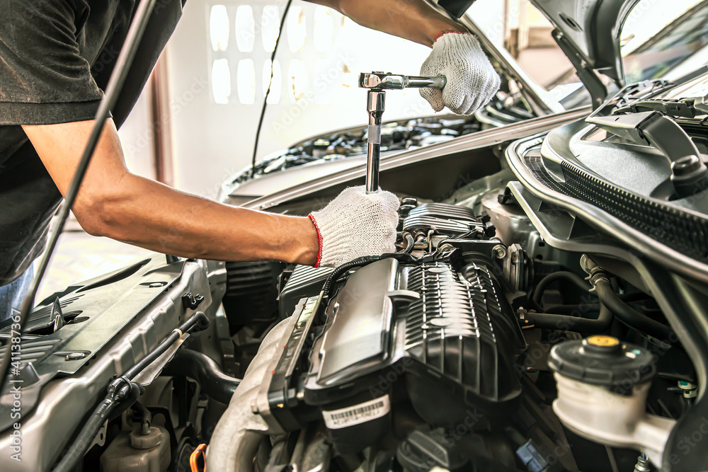 Close-up hands of auto mechanic are using the wrench to repair and maintenance auto engine is problems at car repair shop. Concepts of car care check and fixed and services insurance. Close-up hands of auto mechanic are using the wrench to repair and maintenance auto engine is problems at car repair shop. Concepts of car care check and fixed and services insurance.