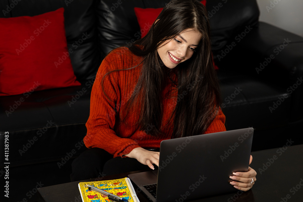 Portrait of a pretty woman working from home on her laptop sitting in living room, young girl studying from home, video conference with friend. Portrait of a pretty woman working from home on her laptop sitting in living room, young girl studying from home, video conference with friend.