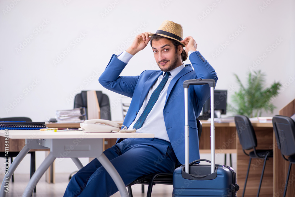 Young male employee preparing for trip in the office