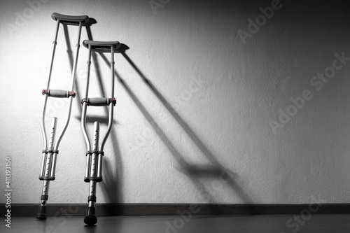 Two crutches stand next to the wall. Concept - leg disease. Crutches as a symbol of people with disabilities. Place for the inscription next to the crutches. Equipment for the disabled.