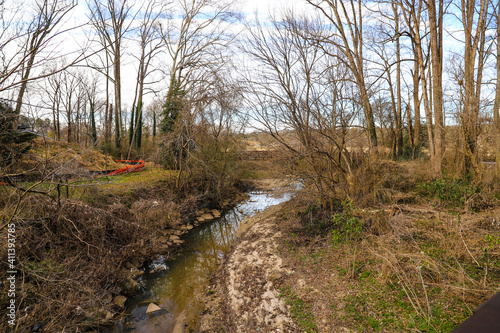 A shot of the still green creek waters with lush green trees and bare tree branches along the banks of the creek with lush green grass at Tanyard Creek Park in the Buckhead area of Atlanta Georgia photo