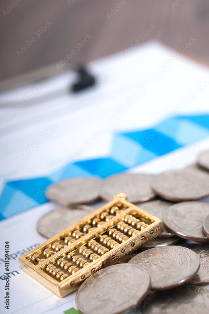 A pile of dollars, coins and golden beads on financial documents