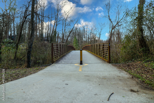 a long brown and yellow iron bridge with smooth concrete pavement across the bridge at Tanyard Creek Park in the Buckhead area of Atlanta Georgia photo