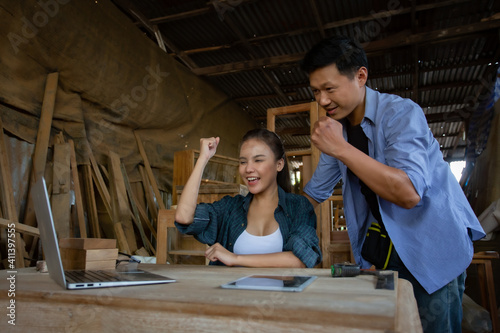 Asian women and men are skilled carpenters holding a tablet, selling wood furniture online, selling things on the website