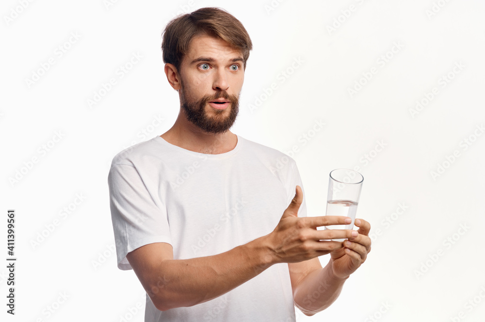 joyful man with a glass of water white t-shirt light background lifestyle gesturing with hands joyful man with a glass of water white t-shirt light background lifestyle gesturing with hands