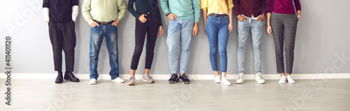 Your shoes says a lot about you. Cropped image of the legs of people in ordinary clothes and shoes standing in a row near the wall. Concept of diverse people in modern business.