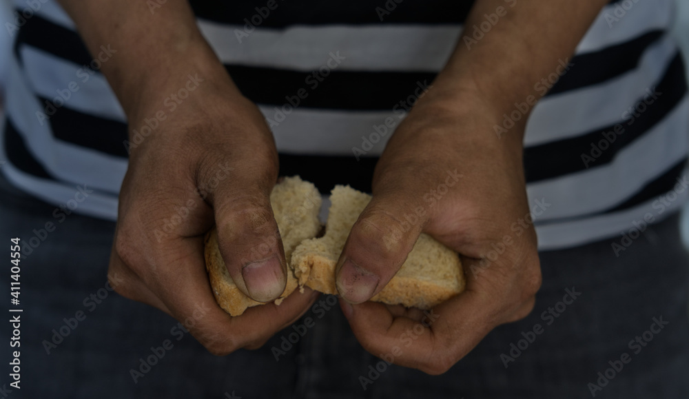 Closeup of dirty hand holding a piece of bread, hunger or poverty concept Closeup of dirty hand holding a piece of bread, hunger or poverty concept