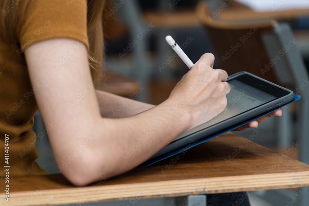 Young woman college students sitting on lecture chair in classroom studying, writing on examination paper answer sheet in doing the final examination test. College students in the classroom Young woman college students sitting on lecture chair in classroom studying, writing on examination paper answer sheet in doing the final examination test. College students in the classroom