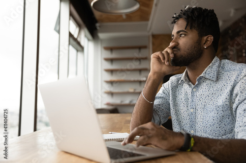 Pensive young afro guy student take distant test exam from home think before type choose correct answer online in pc app. Black male specialist create good cv resume to send email on job seek website photo