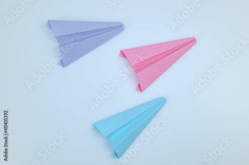 Pink, purple and blue paper airplanes flying in the same direction