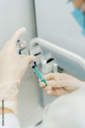 The nurse draws the vaccine into a syringe. Nurse's hands in white rubber gloves
