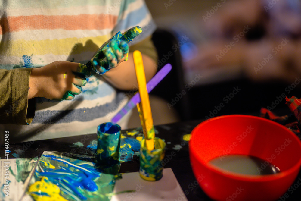 Fototapeta premium Young boy painting with colorful hands. Creativity and art , painting concept