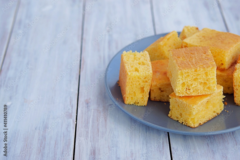 Sliced cornbread on a gray plate on a light wooden background. Corn flour recipes. C