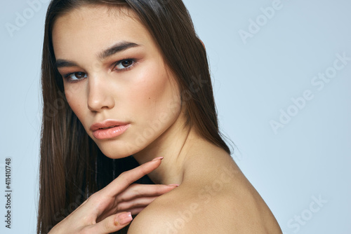 Pretty brunette with bared shoulders long hair body care blue background