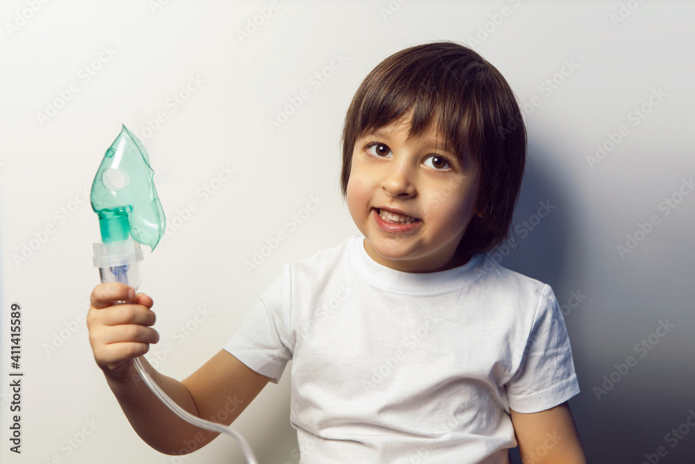 boy child undergoes treatment breathes inhalation green mask on the background of a blue wall in a children's clinic boy child undergoes treatment breathes inhalation green mask on the background of a blue wall in a children's clinic