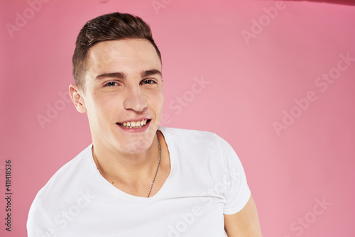 A man in a white t-shirt gestures with his hands emotions pink background studio cropped view