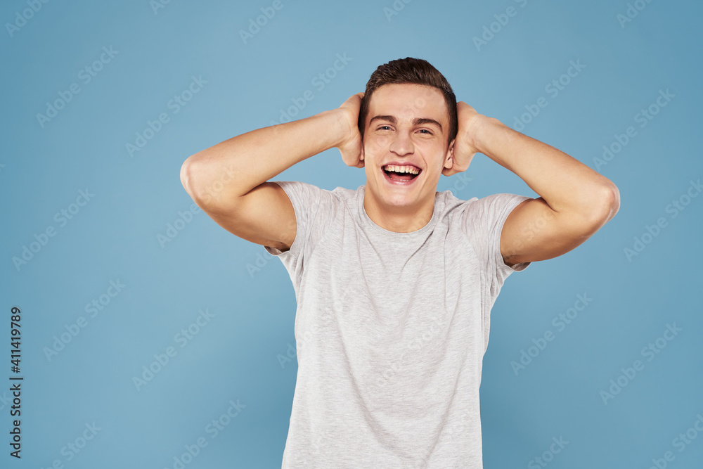 cheerful man in a white t-shirt gesturing with his hands emotions blue background cheerful man in a white t-shirt gesturing with his hands emotions blue background