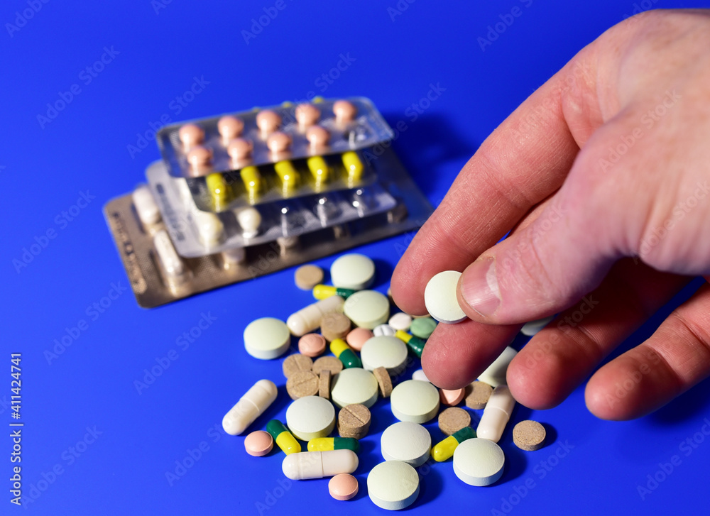 Pills and capsules in hands on blue background. Medicine grade pharmaceutical tablets. Medical pill for maintaining and improving health. Antidepressant addiction and depression concept. Pills and capsules in hands on blue background. Medicine grade pharmaceutical tablets. Medical pill for maintaining and improving health. Antidepressant addiction and depression concept.
