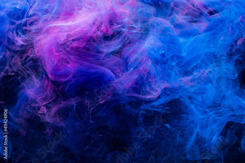 Neon smoke. Colorful background. Paint in water mix design. Cosmic explosion. Glowing vivid blue pink fog cloud flow on dark abstract night sky.