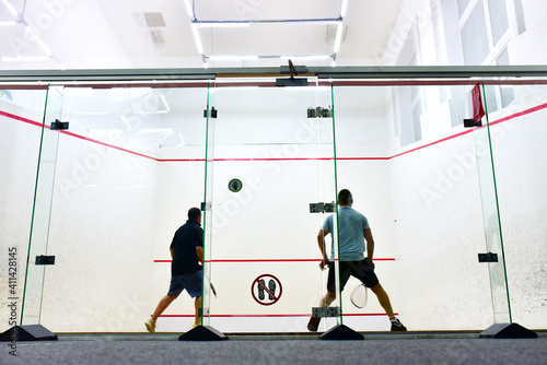 Squash player in action reaching on squash court. Out of focus