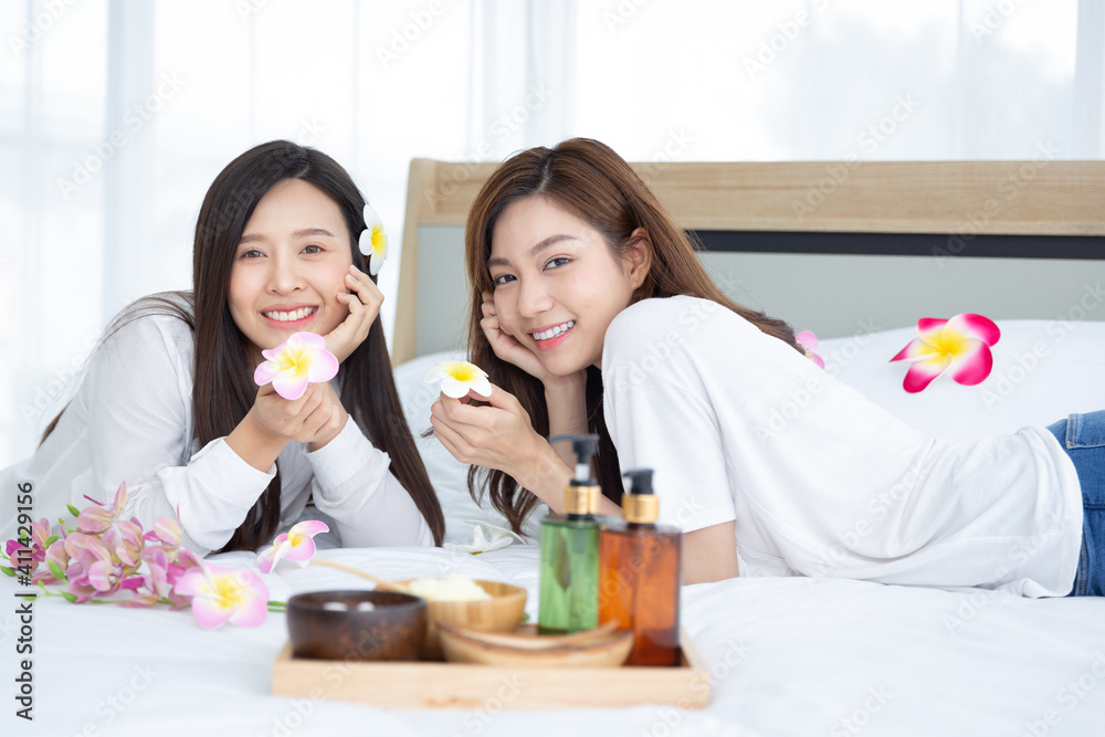 Two young Asian women are enjoying the preparation of spa equipment. Smiling long hair young girl with friends doing DIY spa by herself at home in white bedroom. Two young Asian women are enjoying the preparation of spa equipment. Smiling long hair young girl with friends doing DIY spa by herself at home in white bedroom.