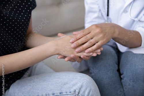 Crop close up of caring doctor or GP hold unhappy distressed female patient hands show support and empathy. Attentive nurse feel supportive comfort and caress upset woman hear bad diagnosis.