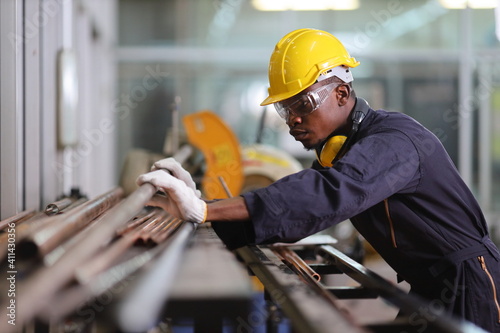 Fotótapéta African American mechanic engineer worker is choosing copper tube for sawing whi