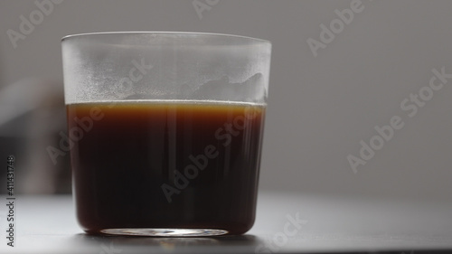 pour water in coffee in tumbler glass on concrete countertop with copy space