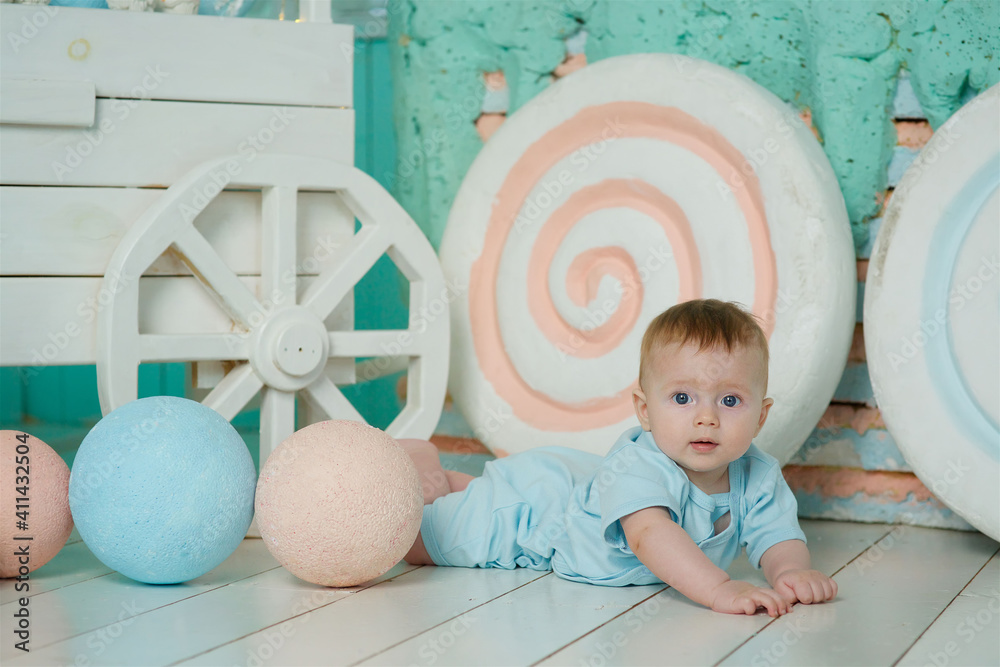 Naklejka premium A baby lies on a soft surface in a bright room, dressed in dark-colored clothing. The concept of childhood