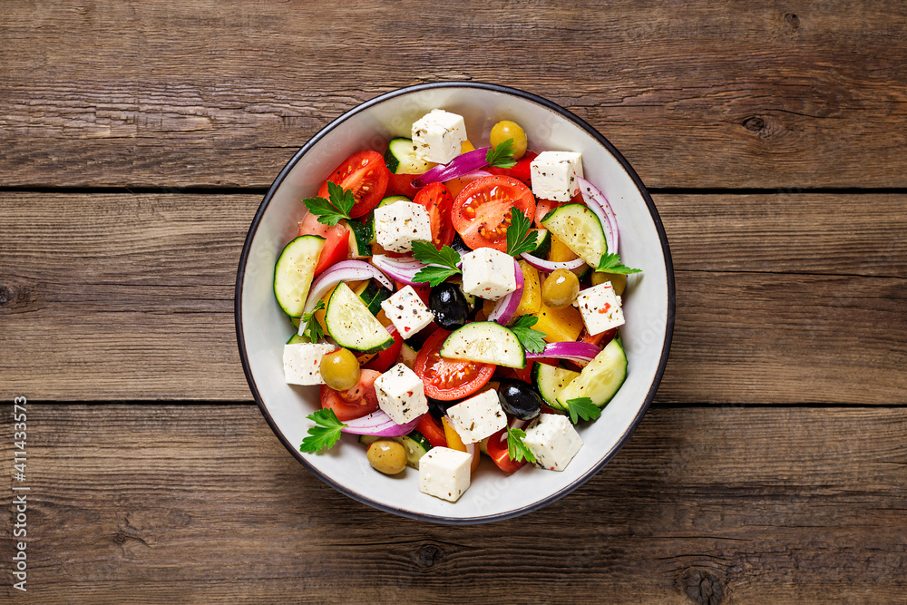 Classic Greek salad with fresh vegetables, feta cheese and  olives. Healthy food. Wooden background. Top view