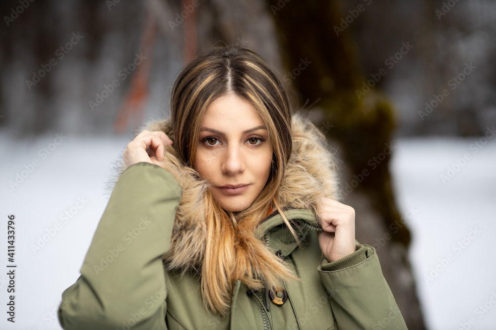 portrait of blonde girl in a green winter coat with a hood with furry fur on the snow in the mountains in winter portrait of blonde girl in a green winter coat with a hood with furry fur on the snow in the mountains in winter