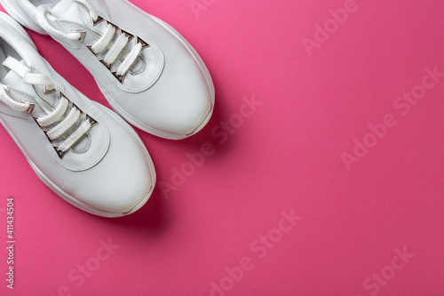 Women's stylish sneakers on a pink background. Lifestyle sneaker sport shoe. Space for text.