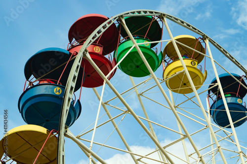 Brightly colored Ferris wheel against the blue sky.